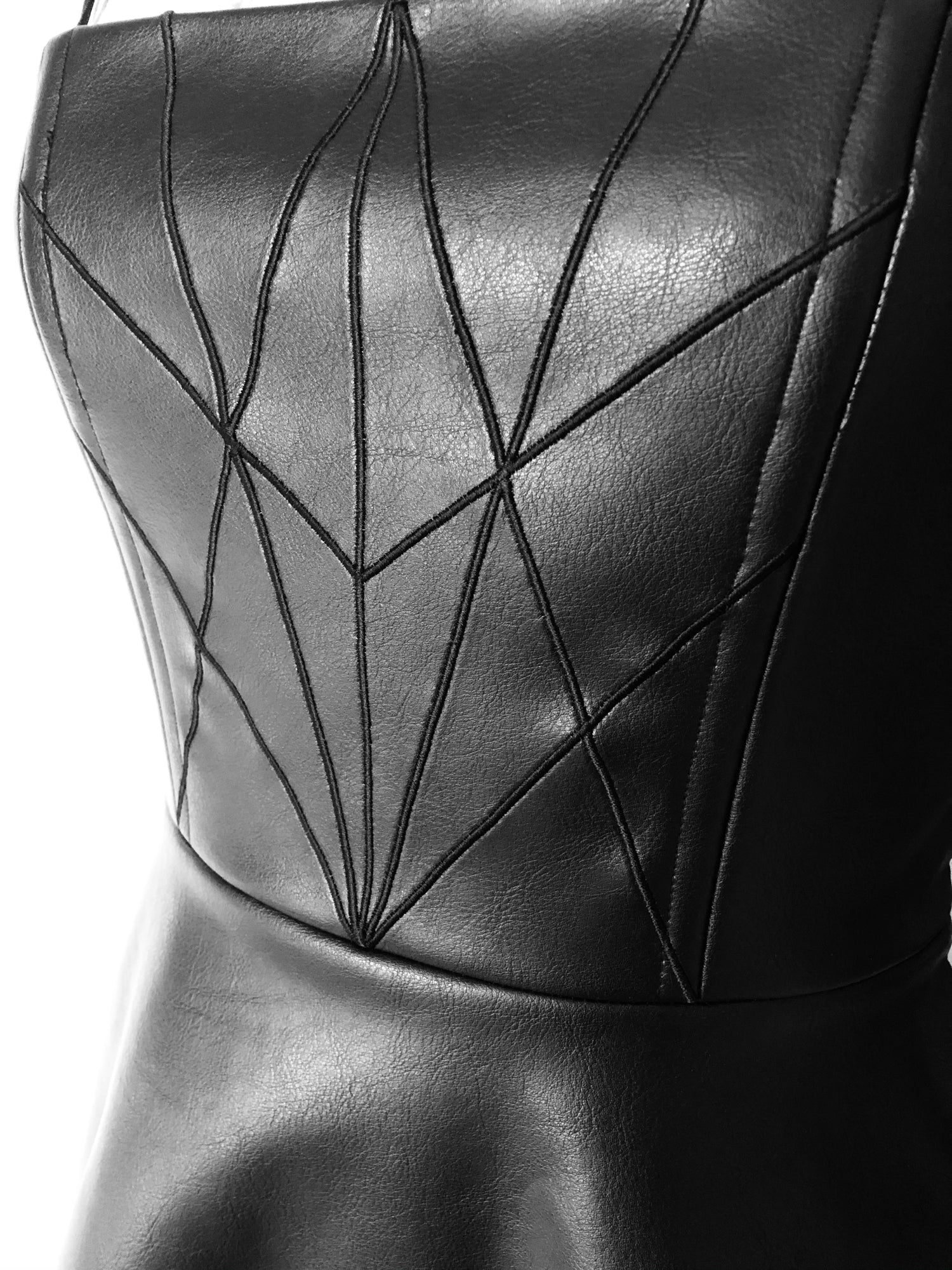 Close-up of black plant-based vegan leather dress with embroidery detail 